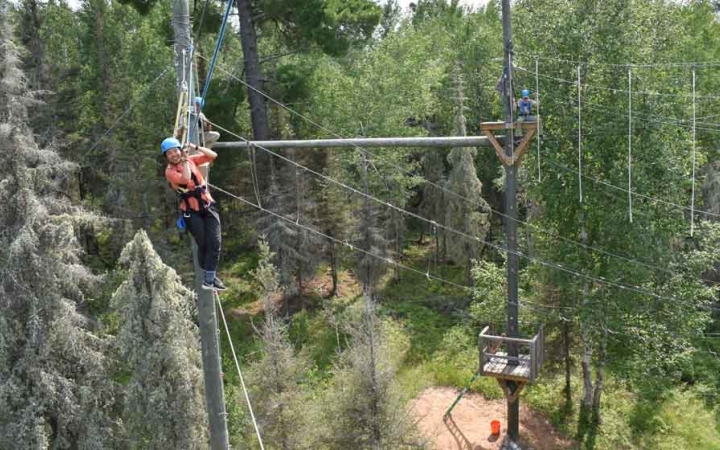 a group of students make their way through a ropes course on an outward bound trip